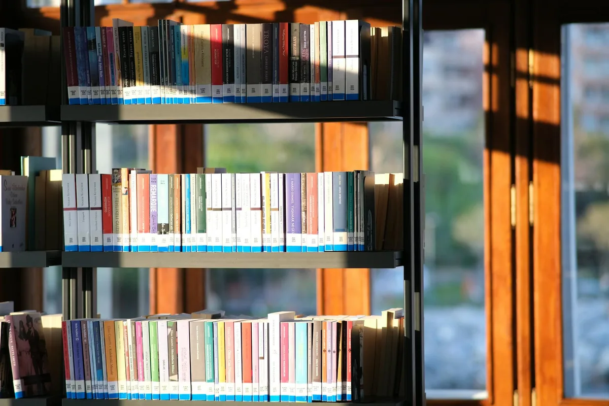 A brightly lit bookshelf filled with books in a library setting.