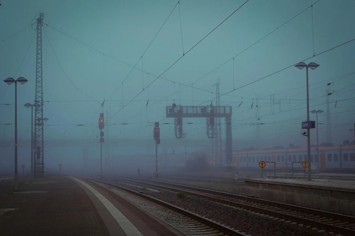 Misty morning at Gießen train station with fog enveloping the tracks and signals.