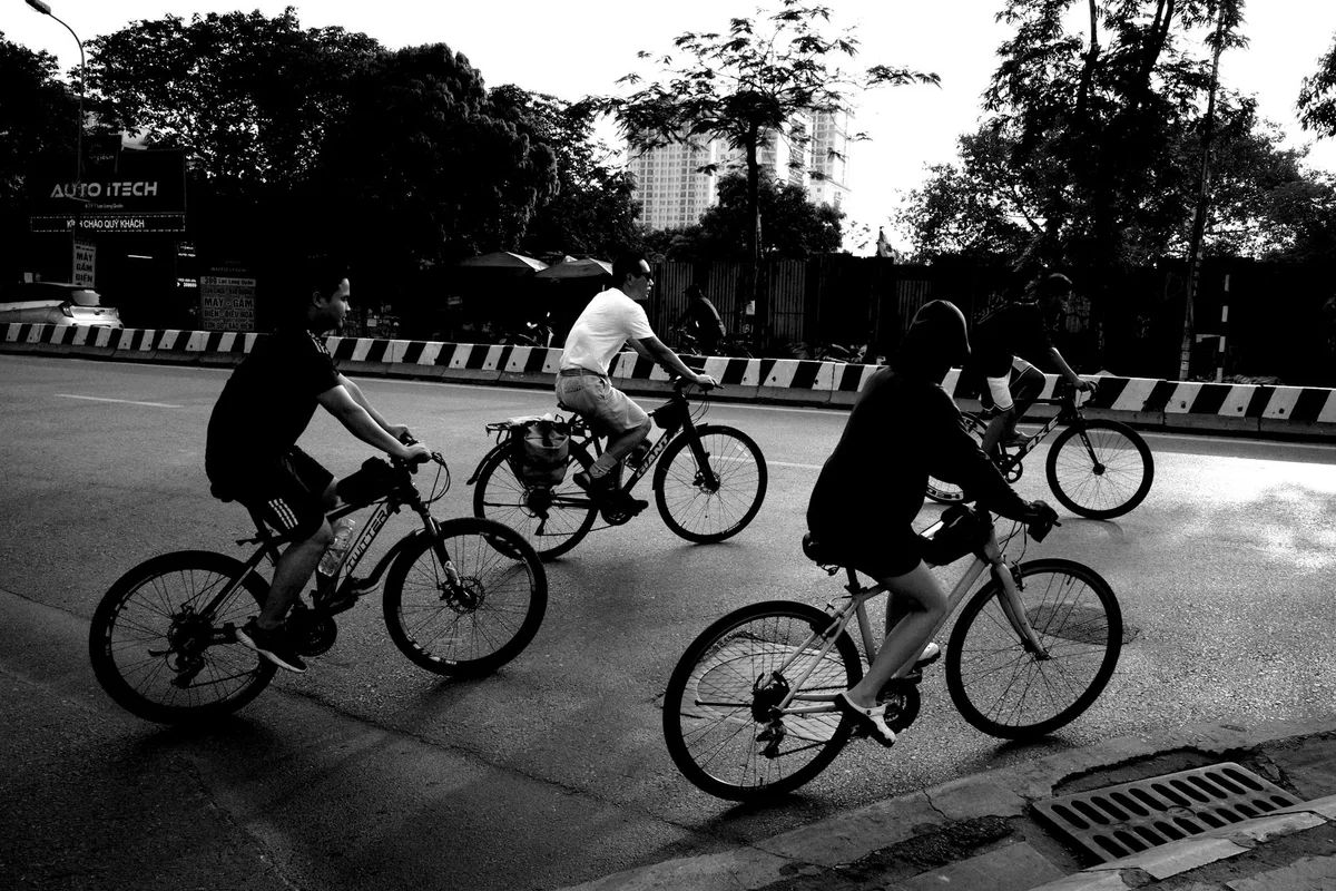 A group of people cycling on an urban road captured in a black and white photograph.