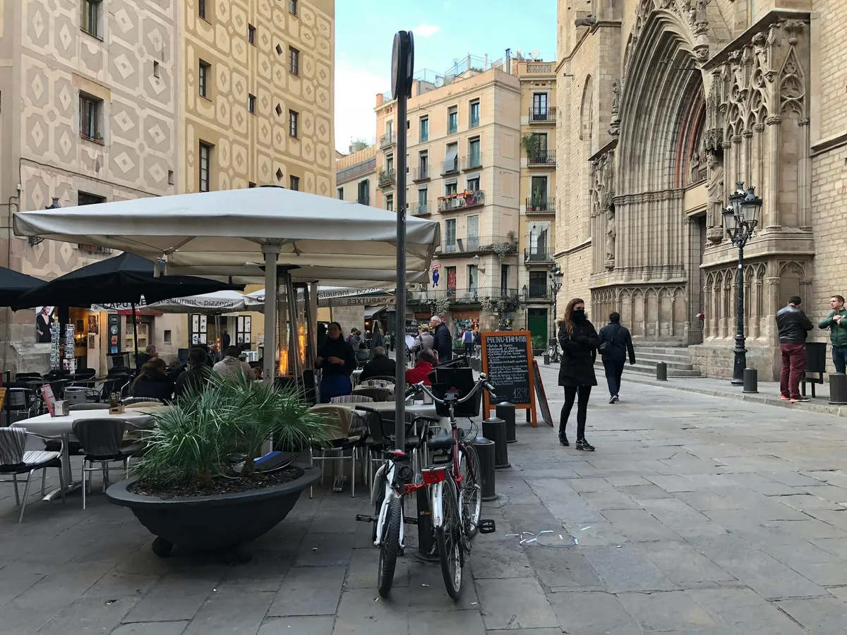 Lively street scene by Santa María del Mar in Barcelona, featuring people, cafes, and architecture.