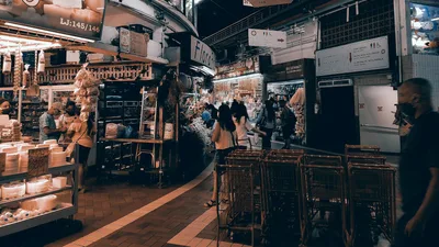 Vibrant indoor market filled with shoppers, food stalls, and lighting. Captures urban market vibe.