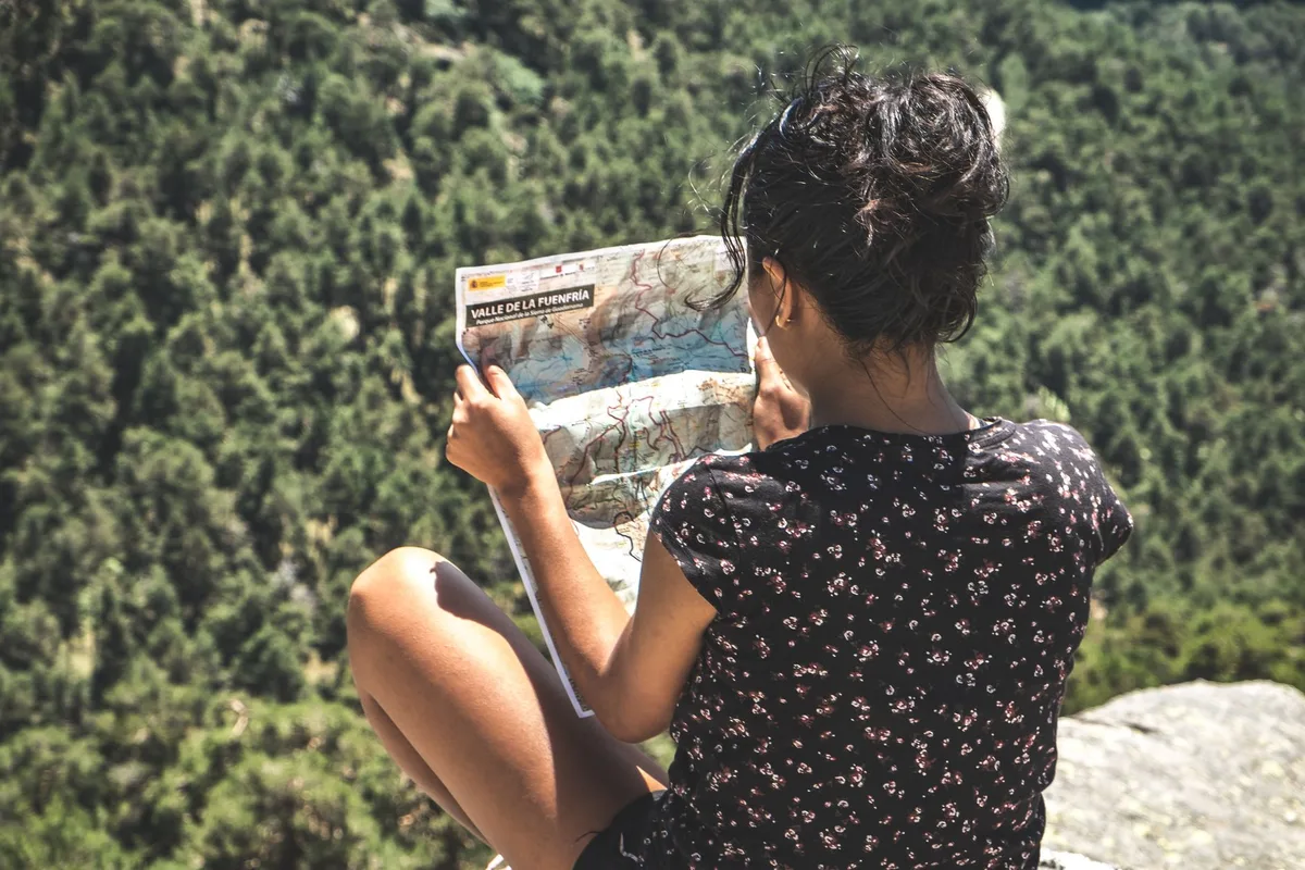 Back view of a woman exploring a mountainous terrain with a map.