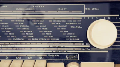 A detailed view of a vintage radio's tuning dial with city stations displayed.