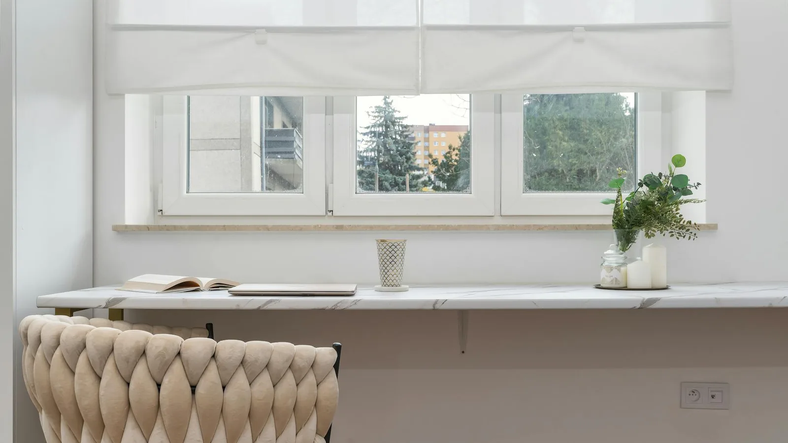 Elegant indoor scene featuring a comfortable armchair, a sleek white desk, and houseplants.
