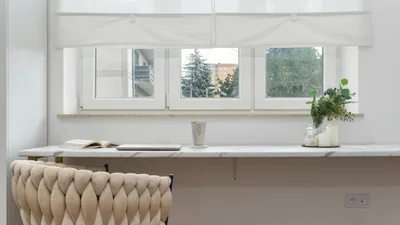Elegant indoor scene featuring a comfortable armchair, a sleek white desk, and houseplants.