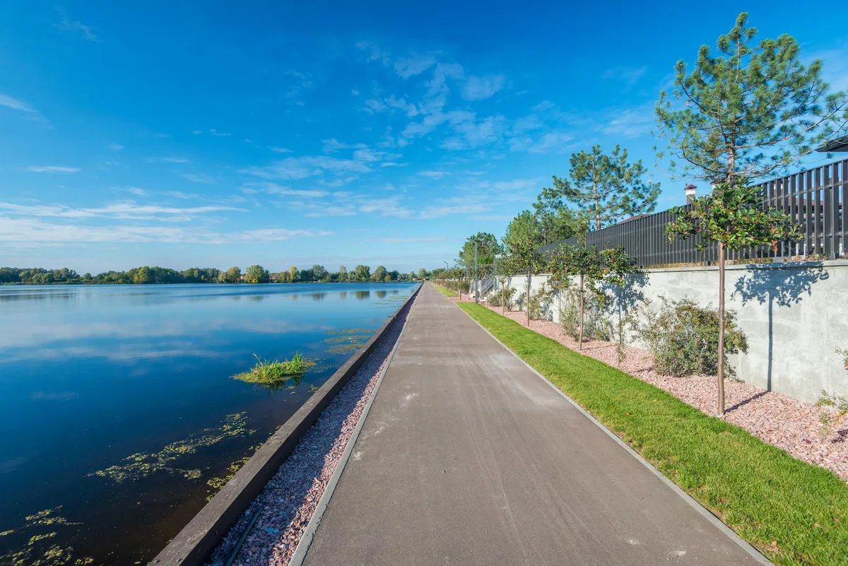 Explore a peaceful riverside promenade with clear skies and lush greenery.