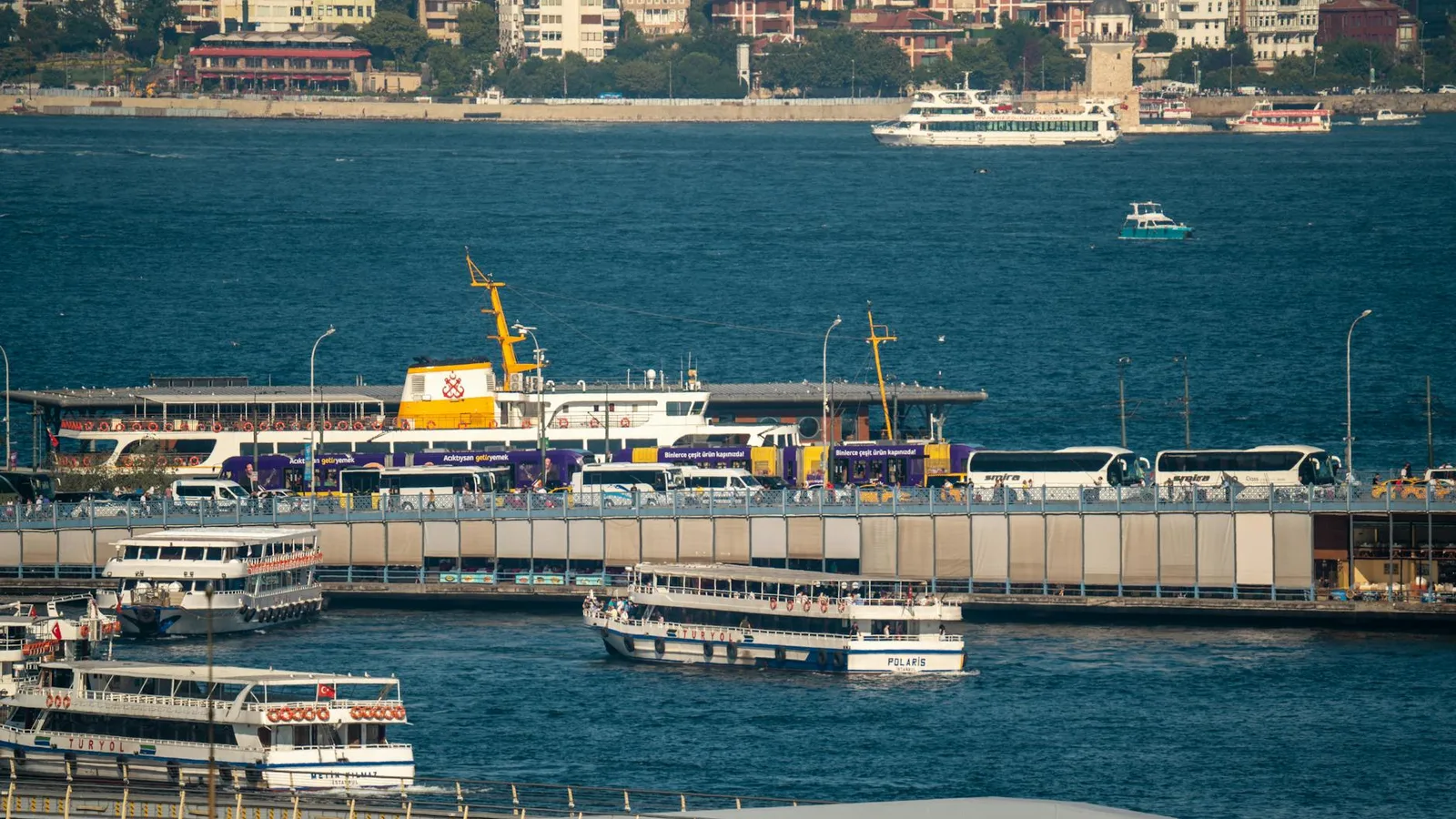 A bustling scene of Istanbul's harbor, featuring ferries and buses in motion.