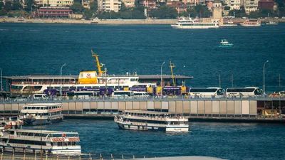A bustling scene of Istanbul's harbor, featuring ferries and buses in motion.