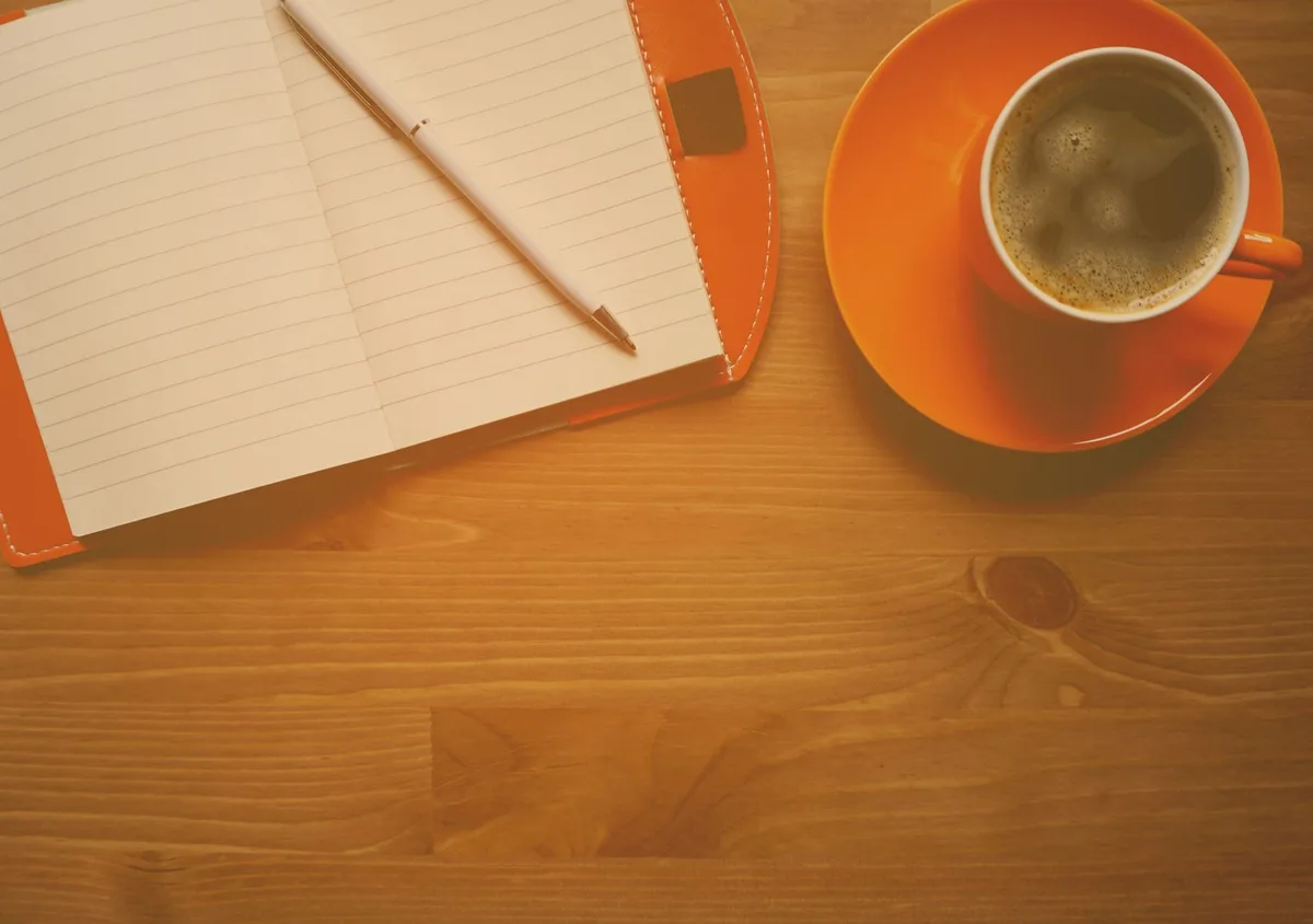 A warm cup of coffee beside an open notebook, perfect for morning reflections.